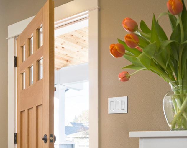 Open front door with flower vase on nearby table