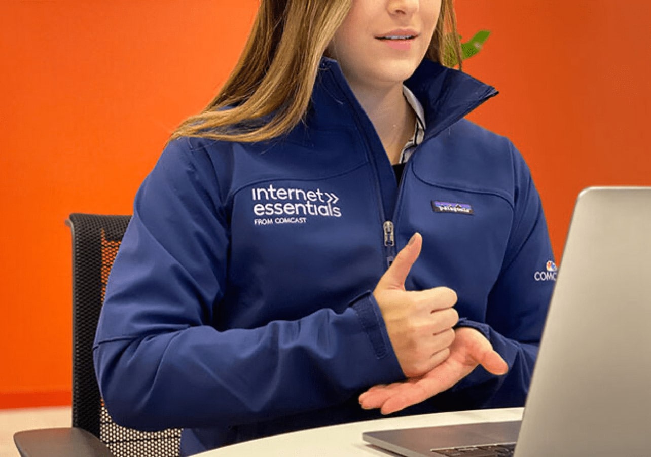 A Comcast employee using sign language to communicate on laptop.